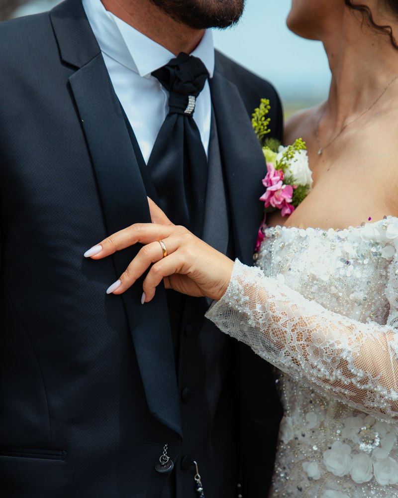 A groom holding his bride close, her hand resting on his lapel