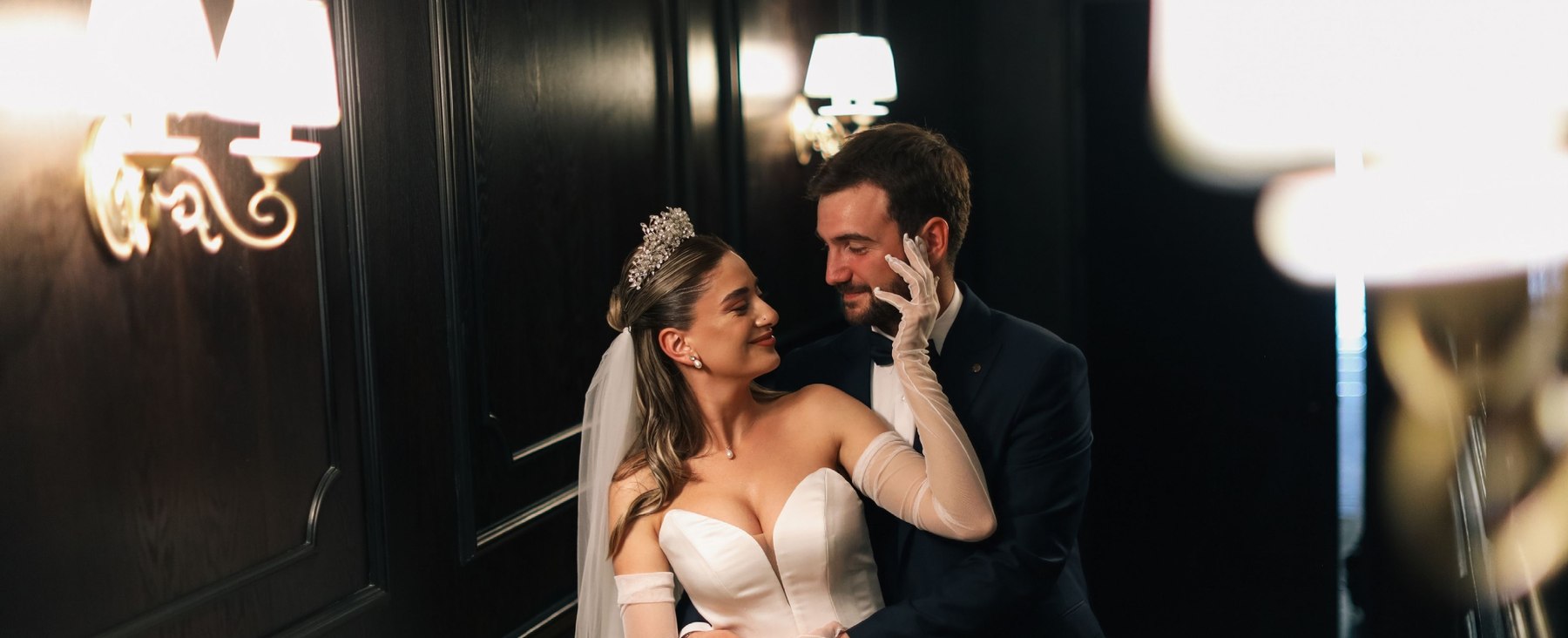 A bride and groom embracing closely in an elegant candlelit ballroom