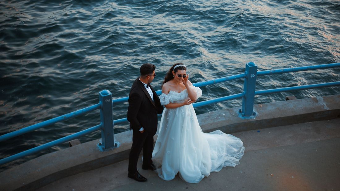 A couple embracing on a seaside promenade railing at dusk