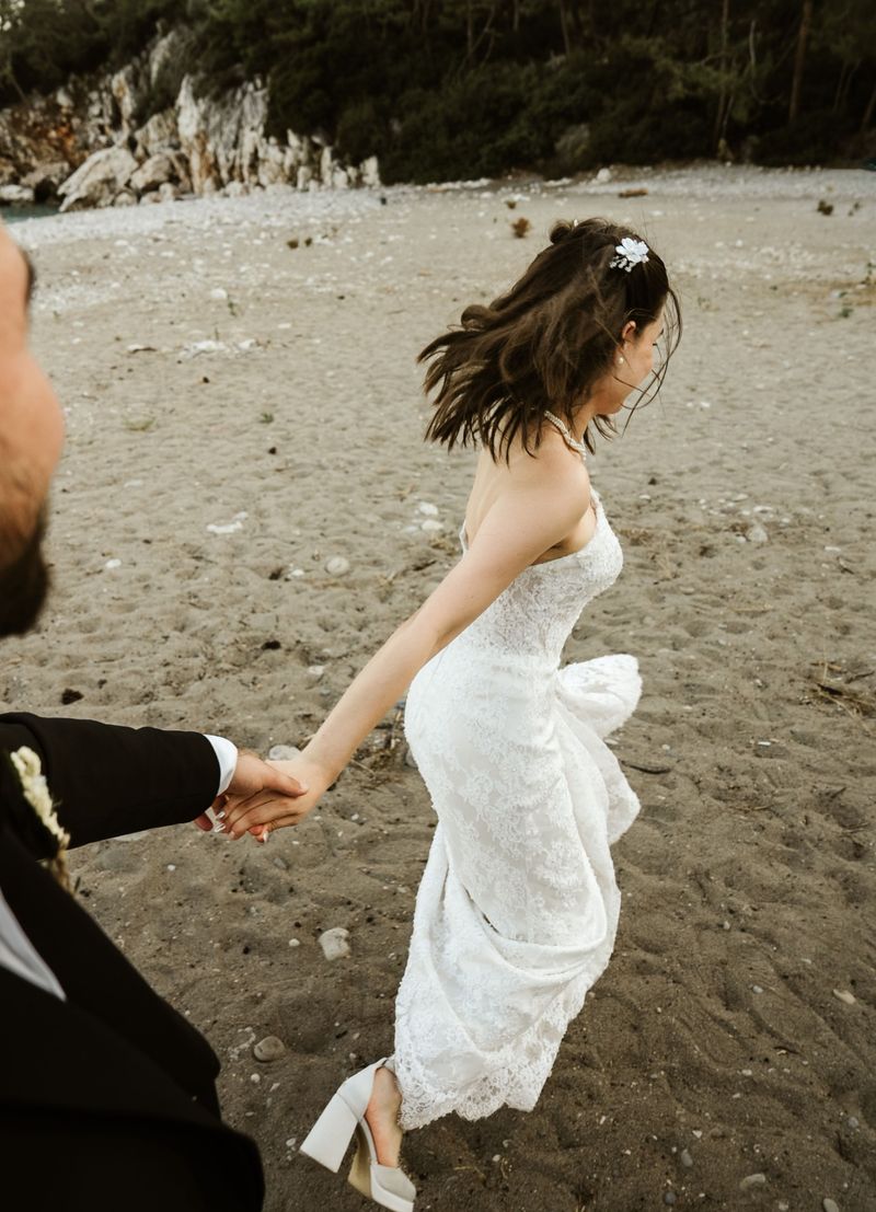 A bride and groom holding hands and walking along a Georgian beach