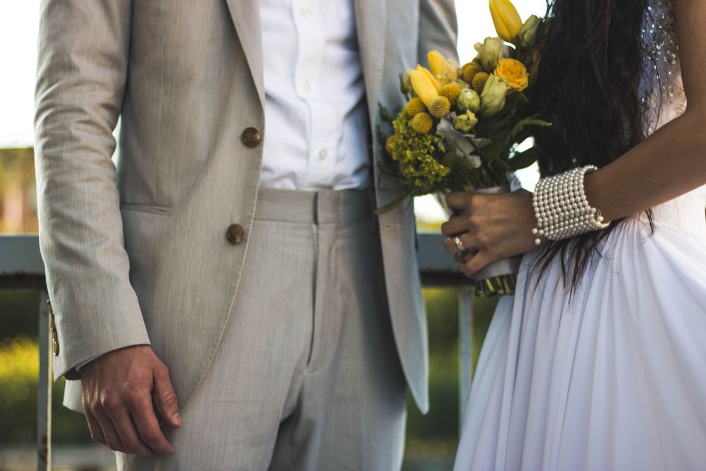 A groom's tailored suit beside the bride's bouquet and jewelry