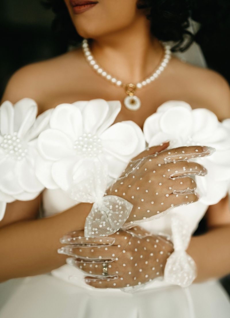 Close-up of a bride's pearl necklace and lace gloves