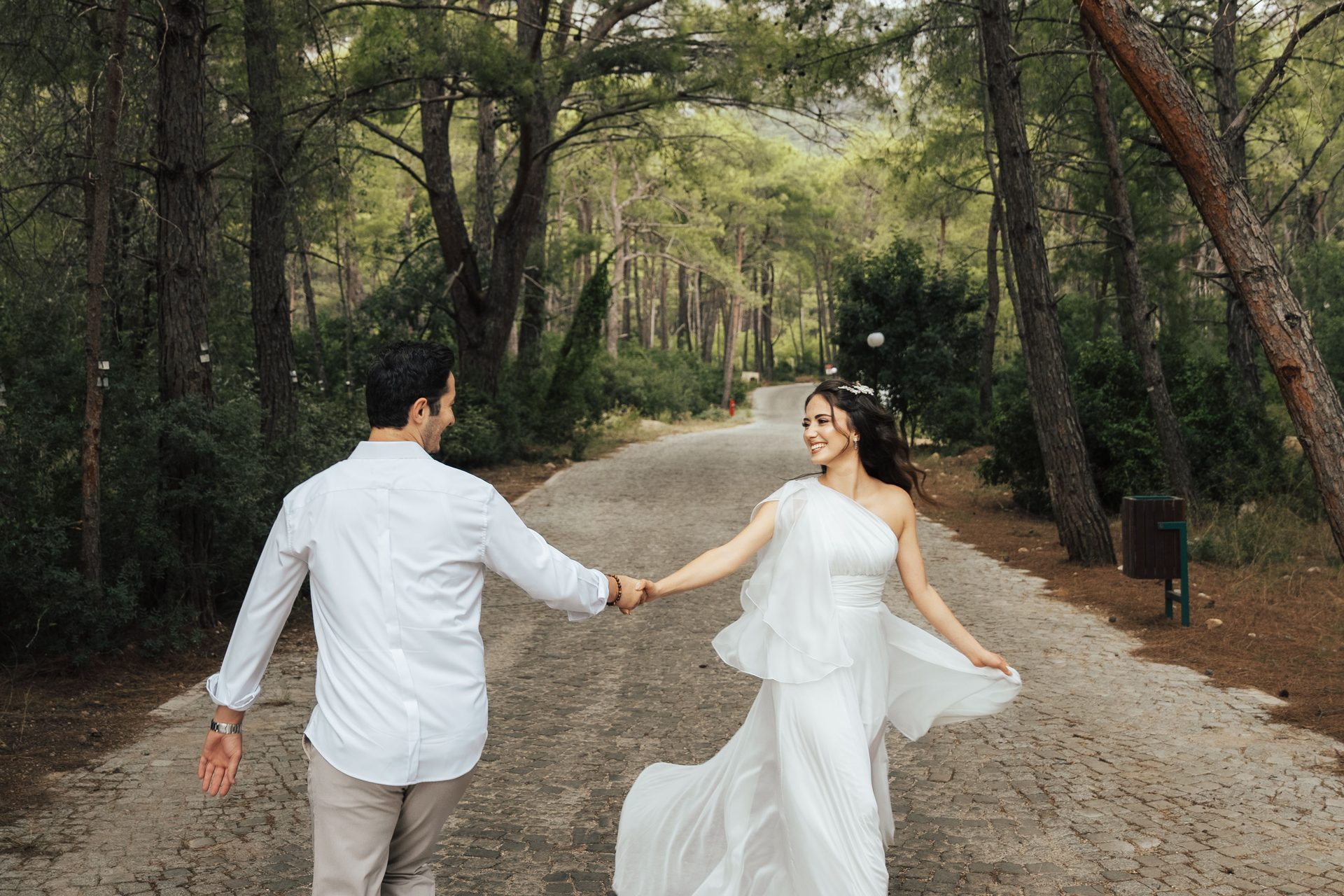 A couple holding hands and walking along a forest path