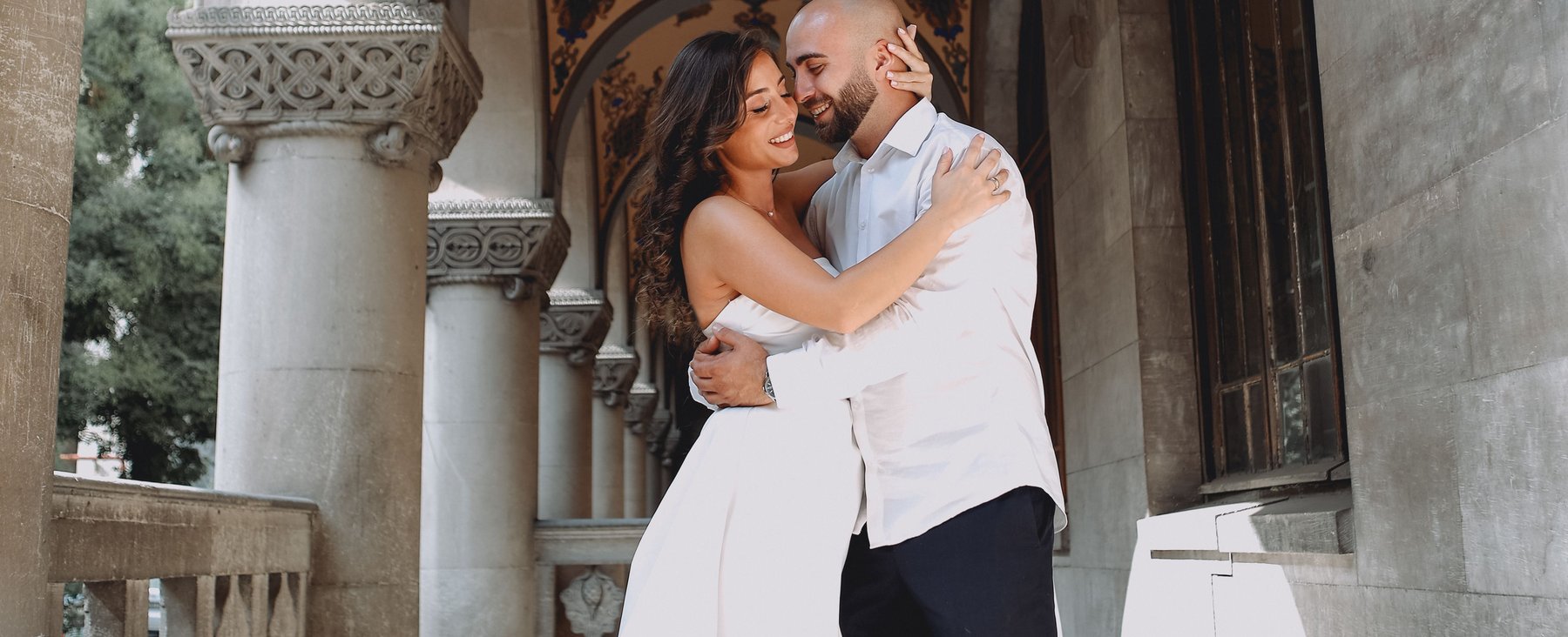 A bride and groom embracing under an ornate painted archway