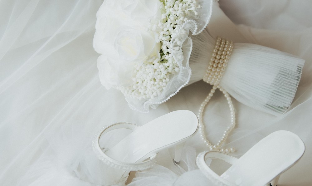 Bridal shoes, a bouquet and pearls laid out on a veil