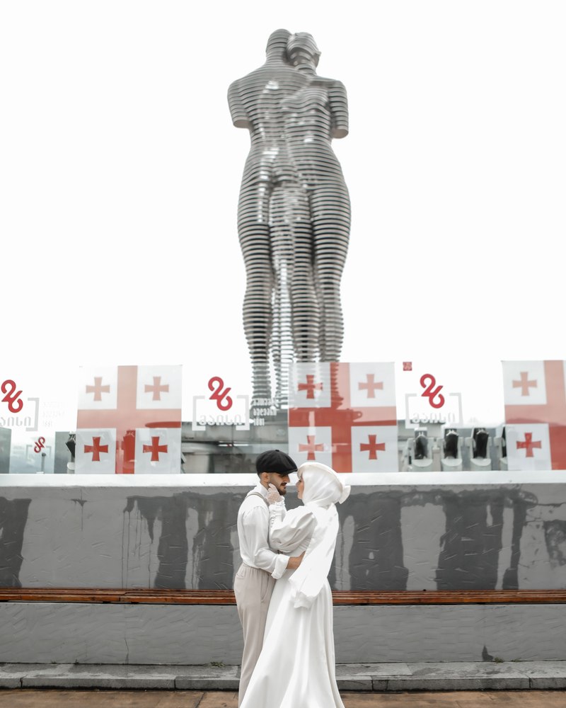 A bride and groom embracing beneath the moving Ali and Nino statue in Batumi