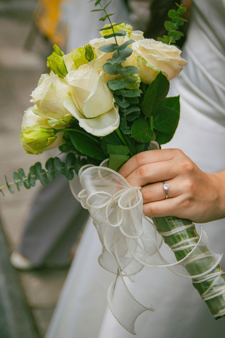 A bride holding a bouquet of white roses and eucalyptus