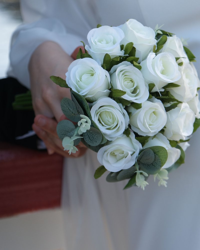 A bride holding a bouquet of white roses and eucalyptus