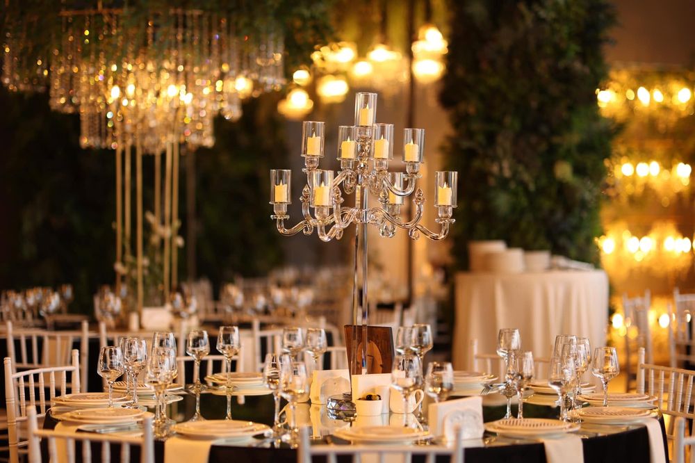 A wedding reception hall with candelabras, crystal chandeliers and set tables