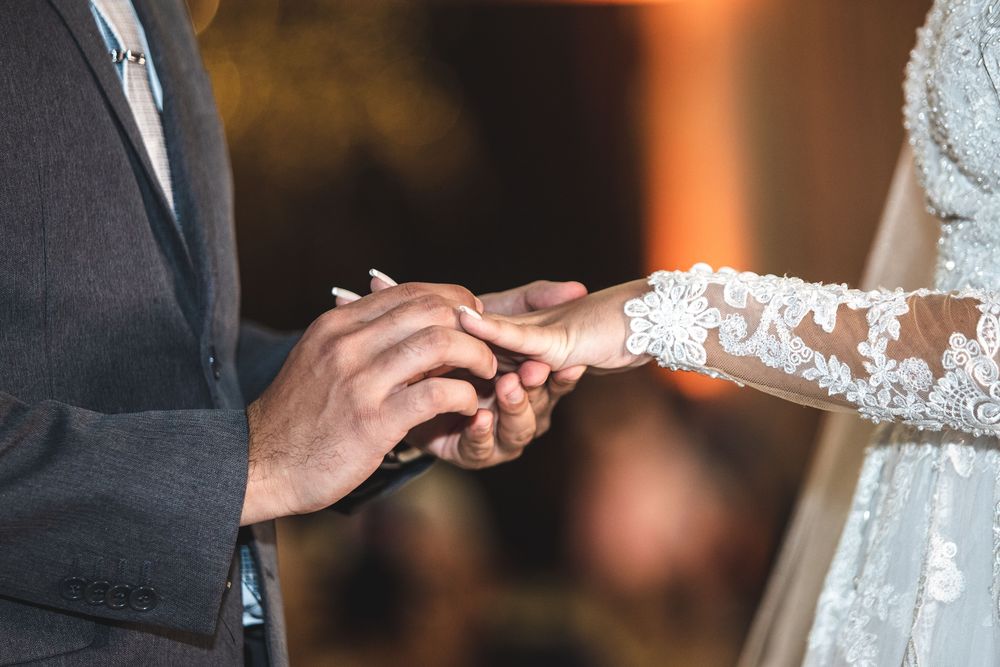 Close-up of a groom placing a ring on the bride's hand during the ceremony