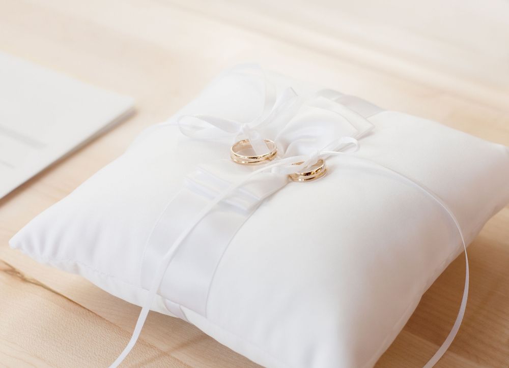 Wedding rings resting on a white ring-bearer pillow