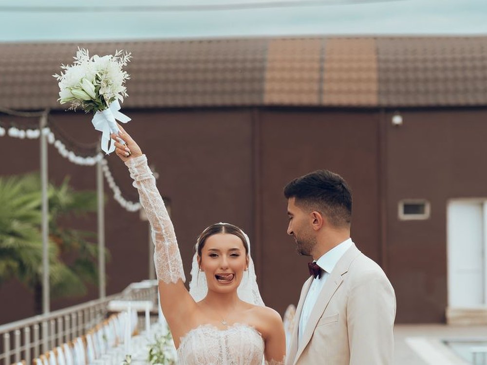 A bride and groom celebrating on a seaside terrace set for a reception