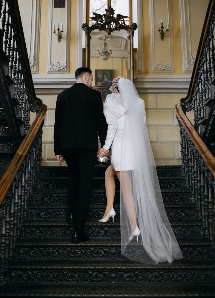 A bride and groom descending an elegant historic staircase