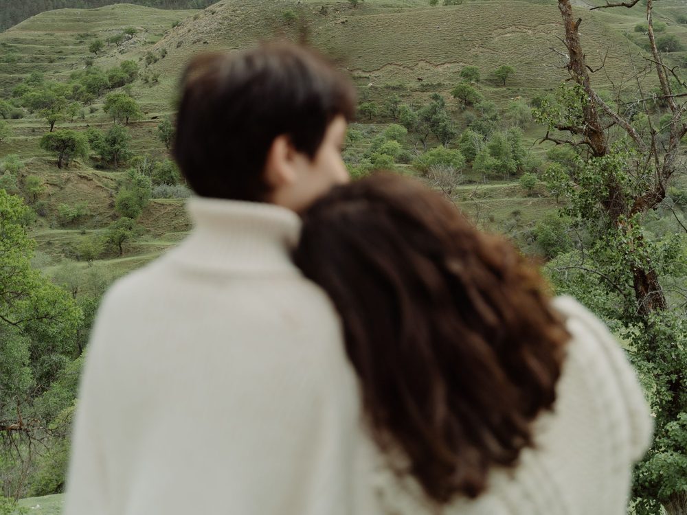 A couple embracing with green Georgian hills behind them