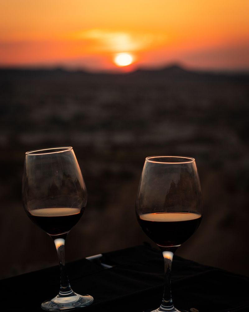 Two glasses of red wine on a table at sunset