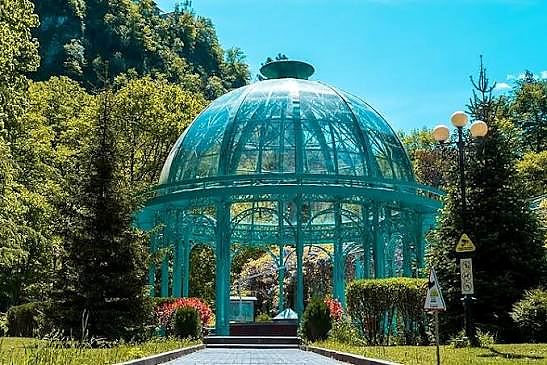 Ornate green gazebo in Borjomi Central Park surrounded by forest